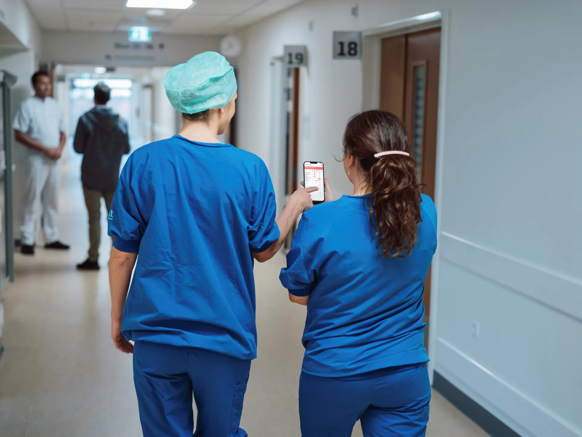 Nurses viewing a phone displaying the Columna Flow Command Centre interface in a hospital hallway.