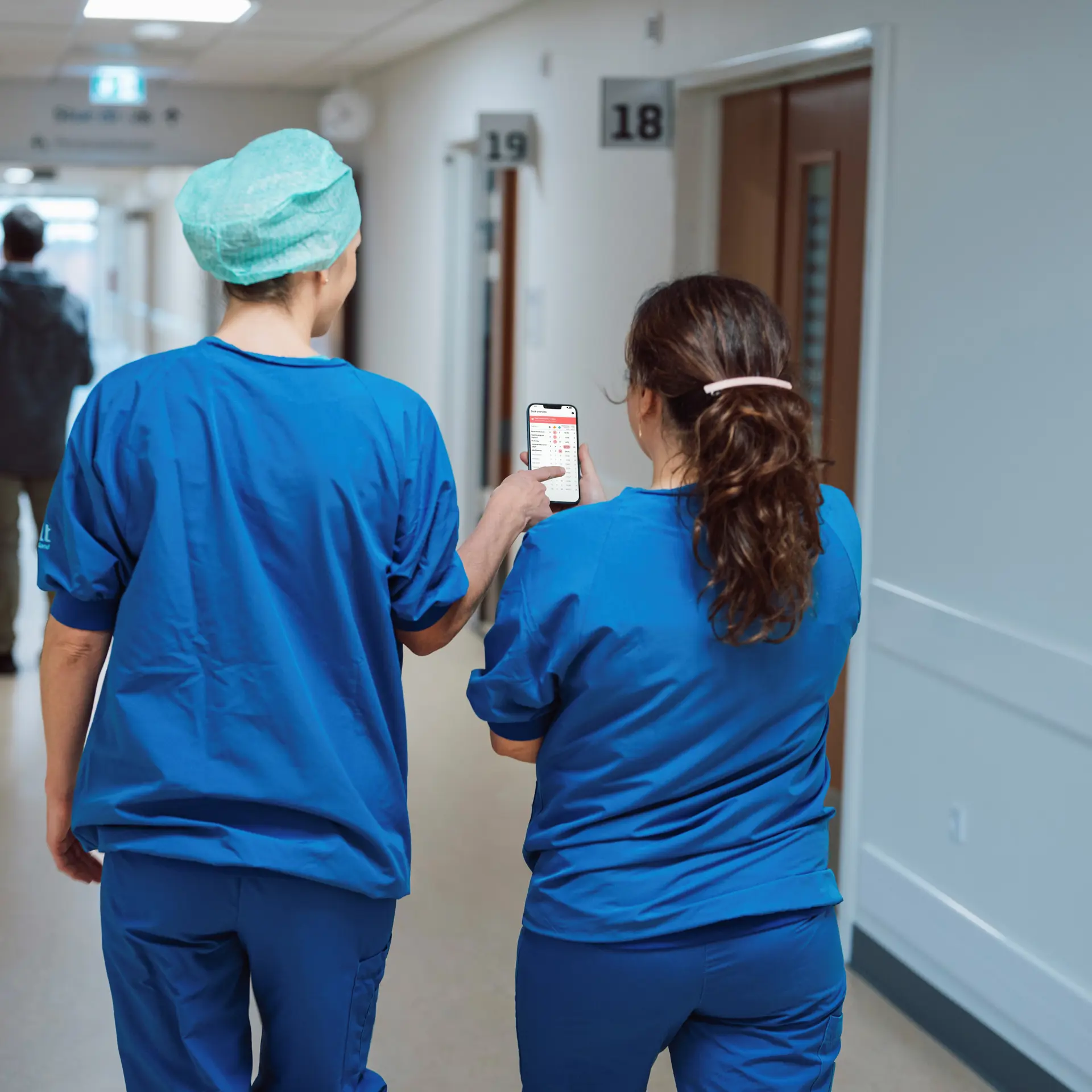 Nurses viewing a phone displaying the Columna Flow Command Centre interface in a hospital hallway.