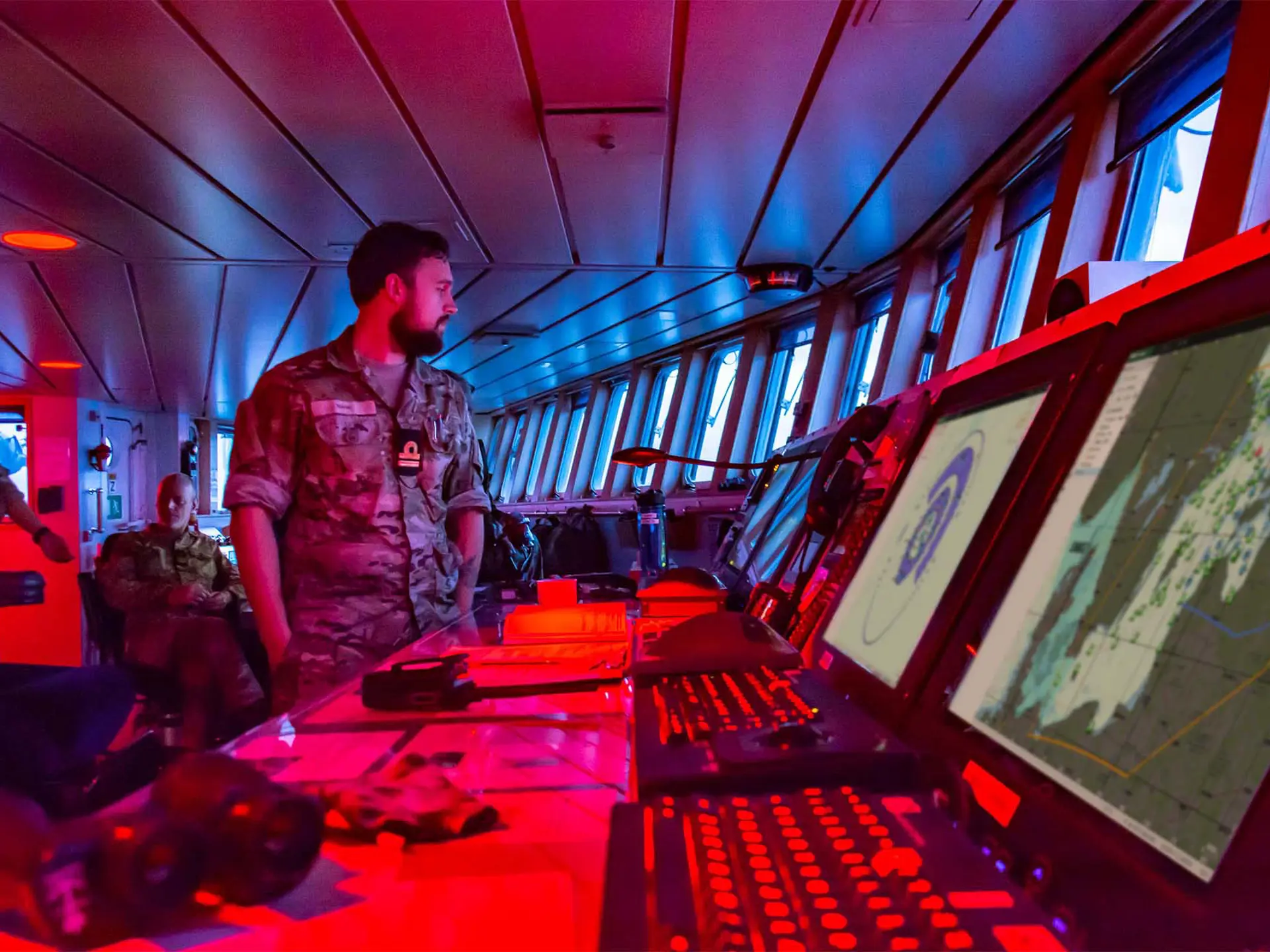 Naval commander monitoring ship’s bridge screens with SitaWare Maritime software for situational awareness and mission planning.
