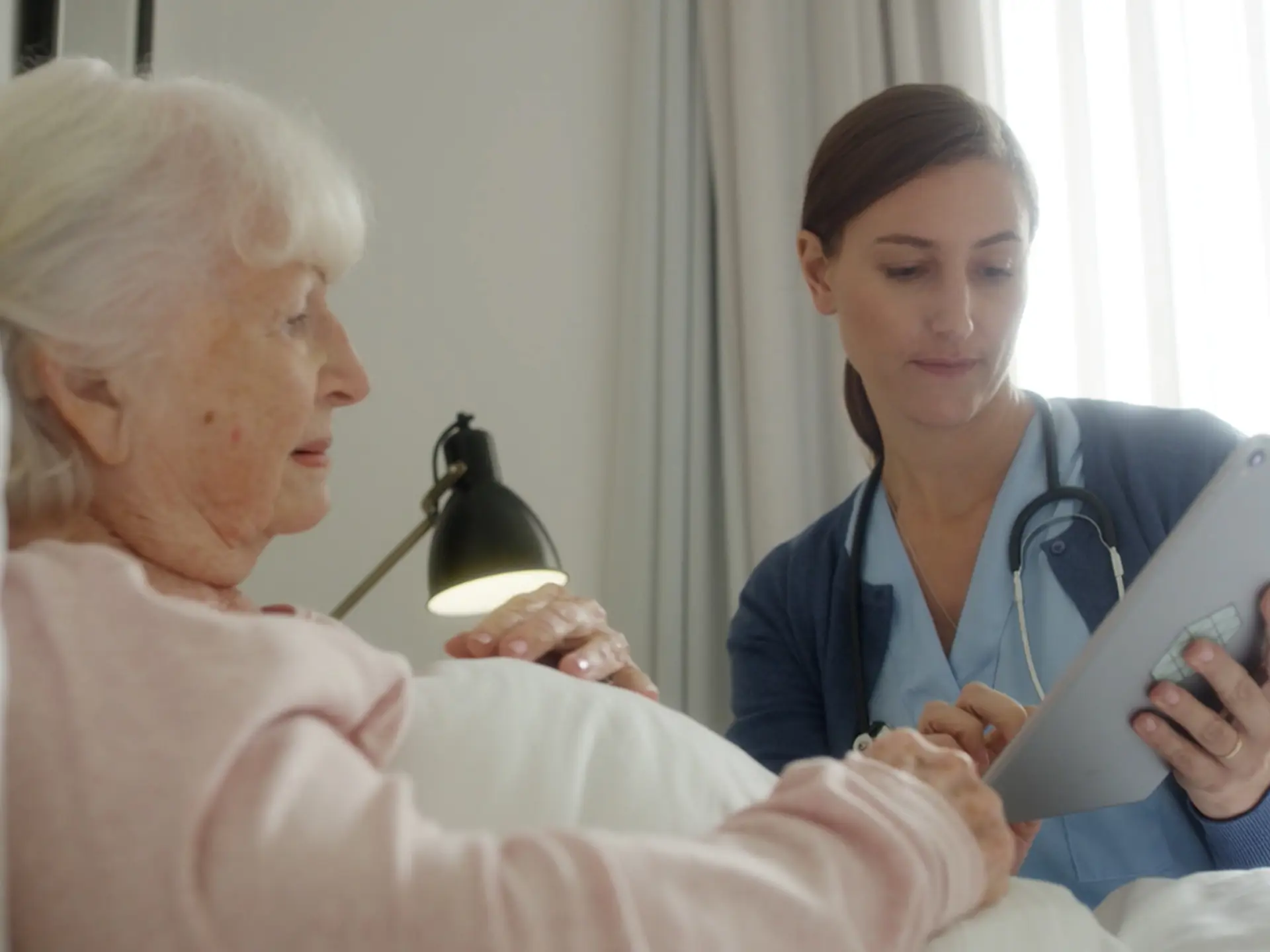 Caregiver With Tablet At Citizen Bedside
