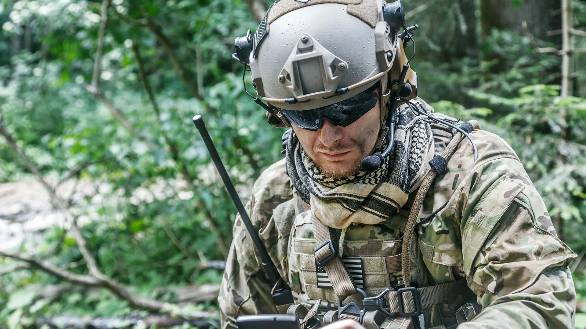 Soldier with mobile device an HF radio in woods