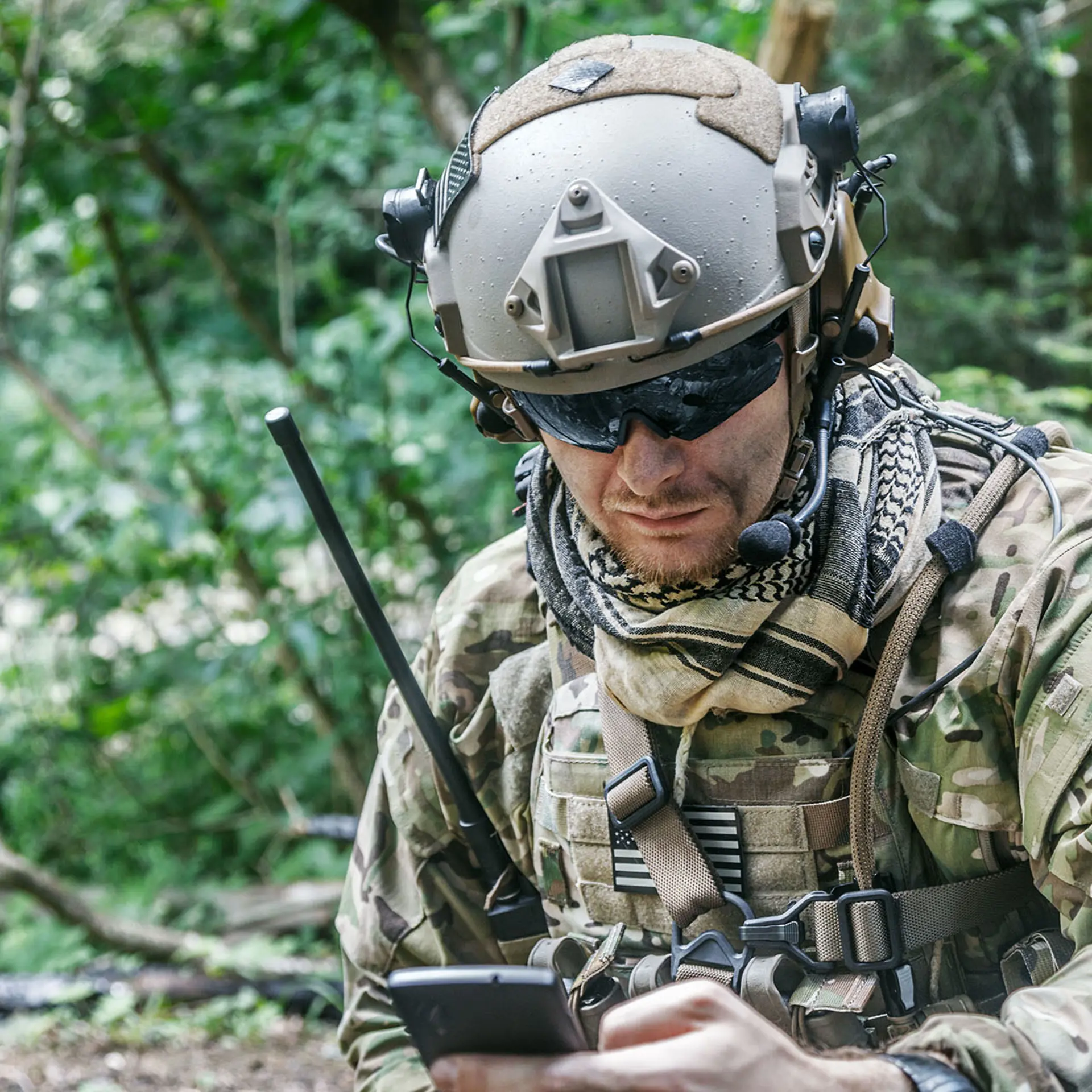 Soldier with mobile device an HF radio in woods