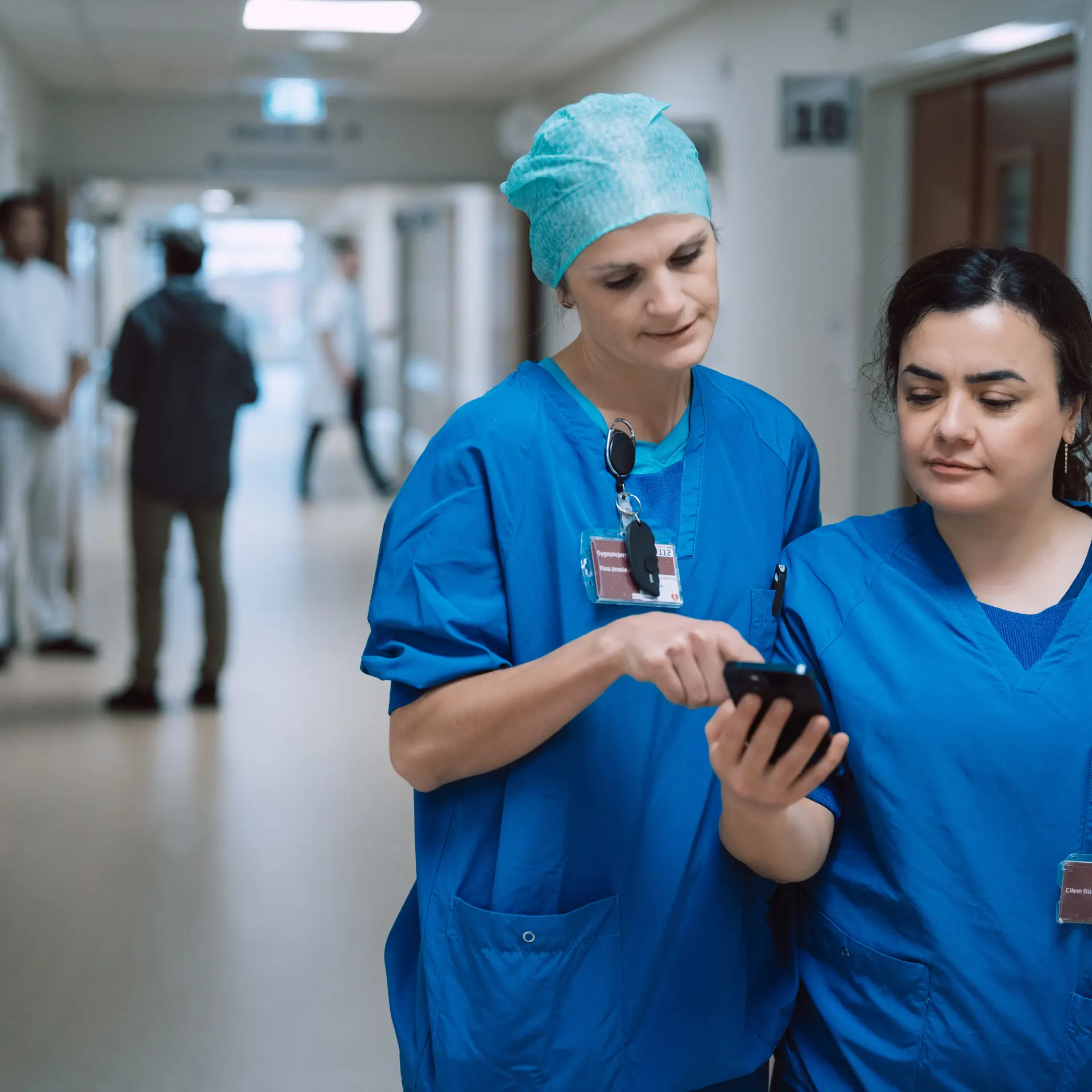 Nurses Looking At Columna Flow on Phone In Hospital Hallway