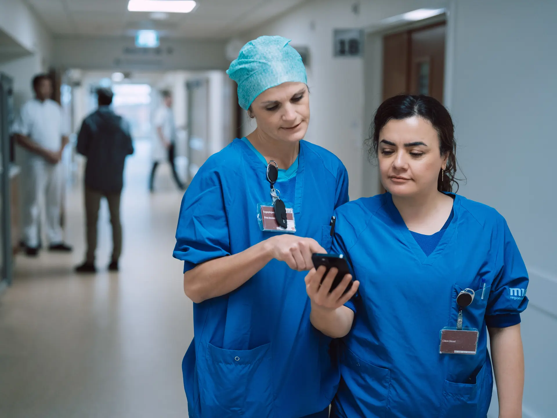 Nurses Looking At Columna Flow on Phone In Hospital Hallway
