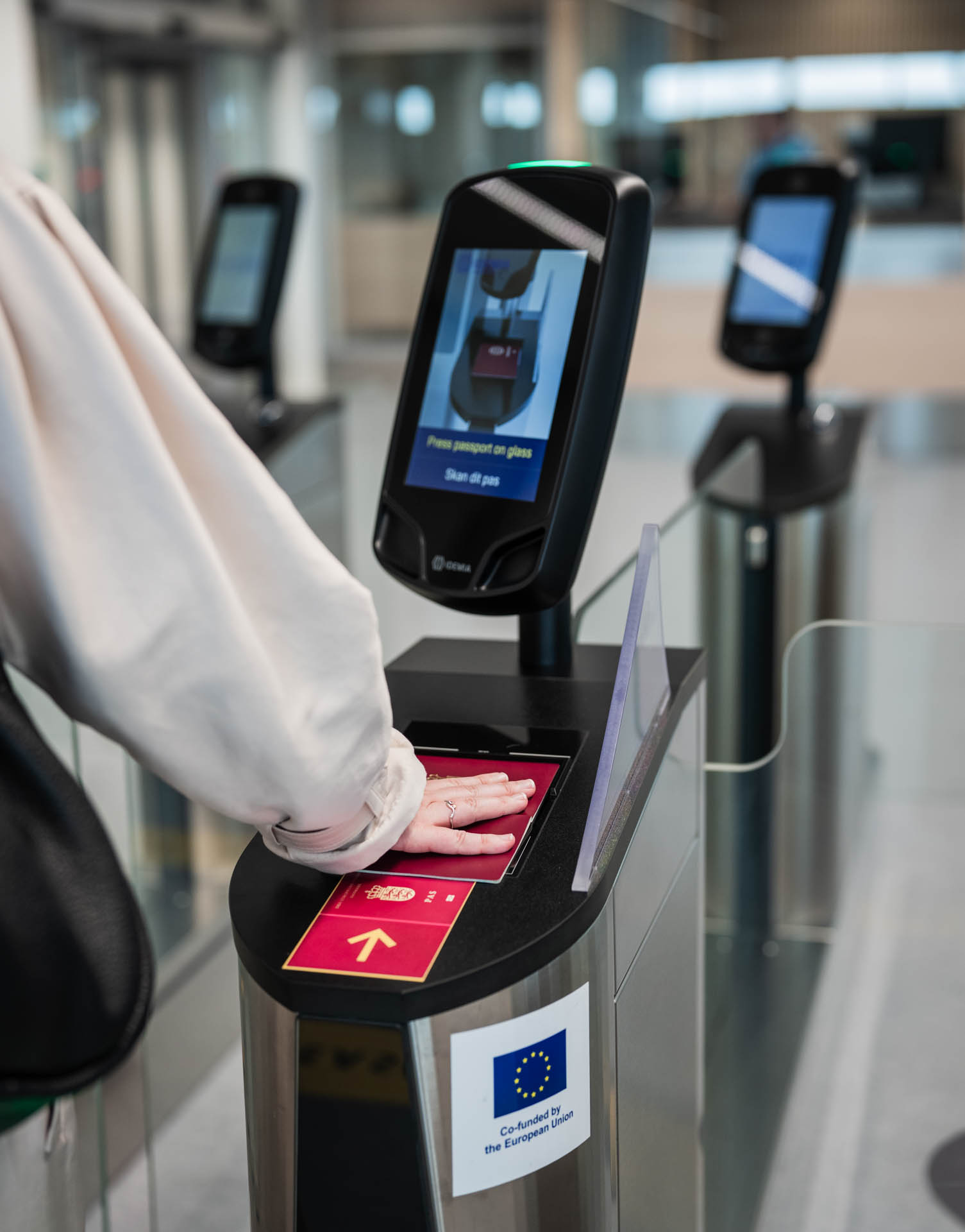 Close-up of a traveler scanning their hand at an automated biometric access control terminal at an airport checkpoint