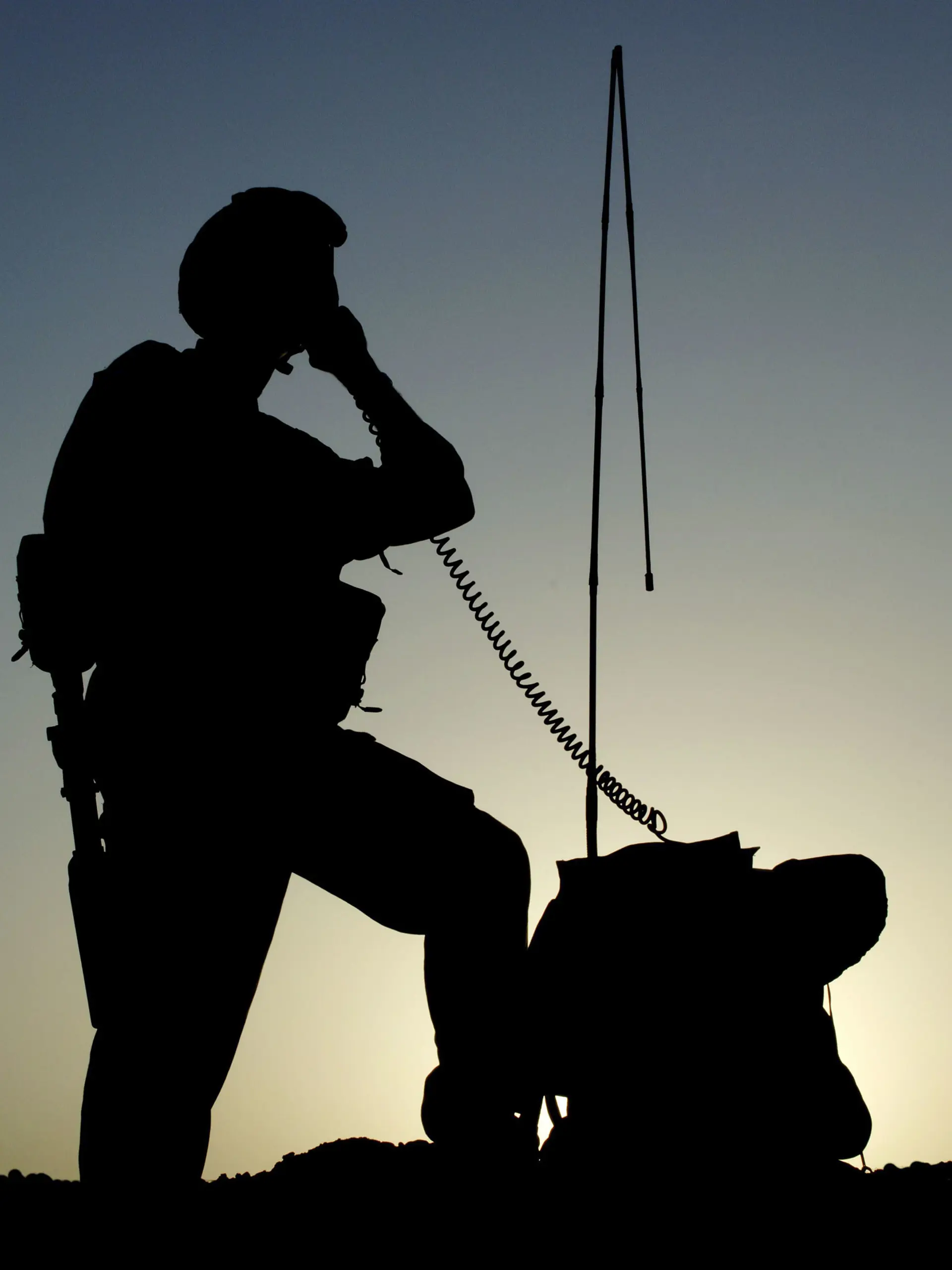 Soldier in silhouette operating a radio 