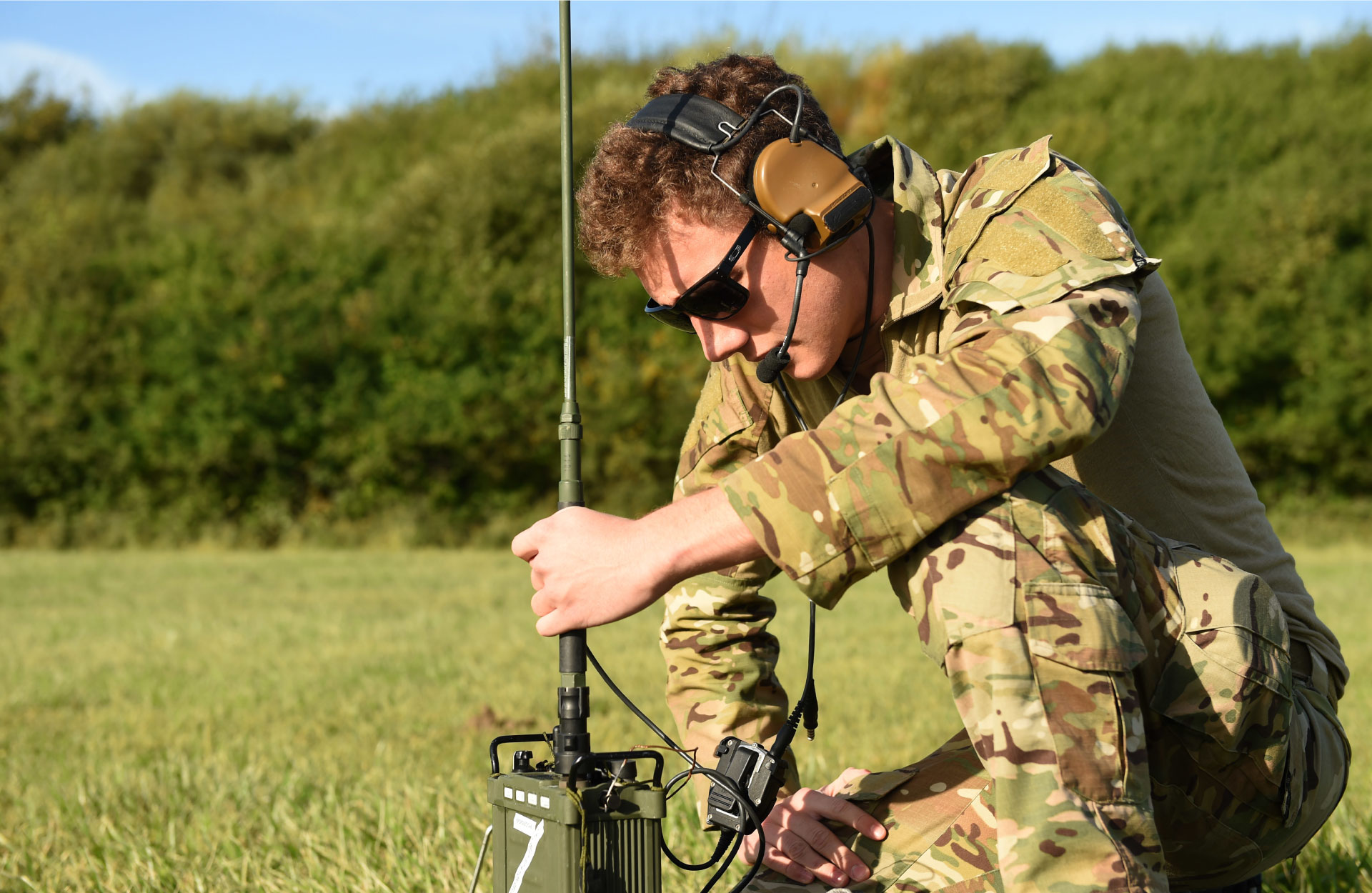 Solider sitting on grass and testing HF radio