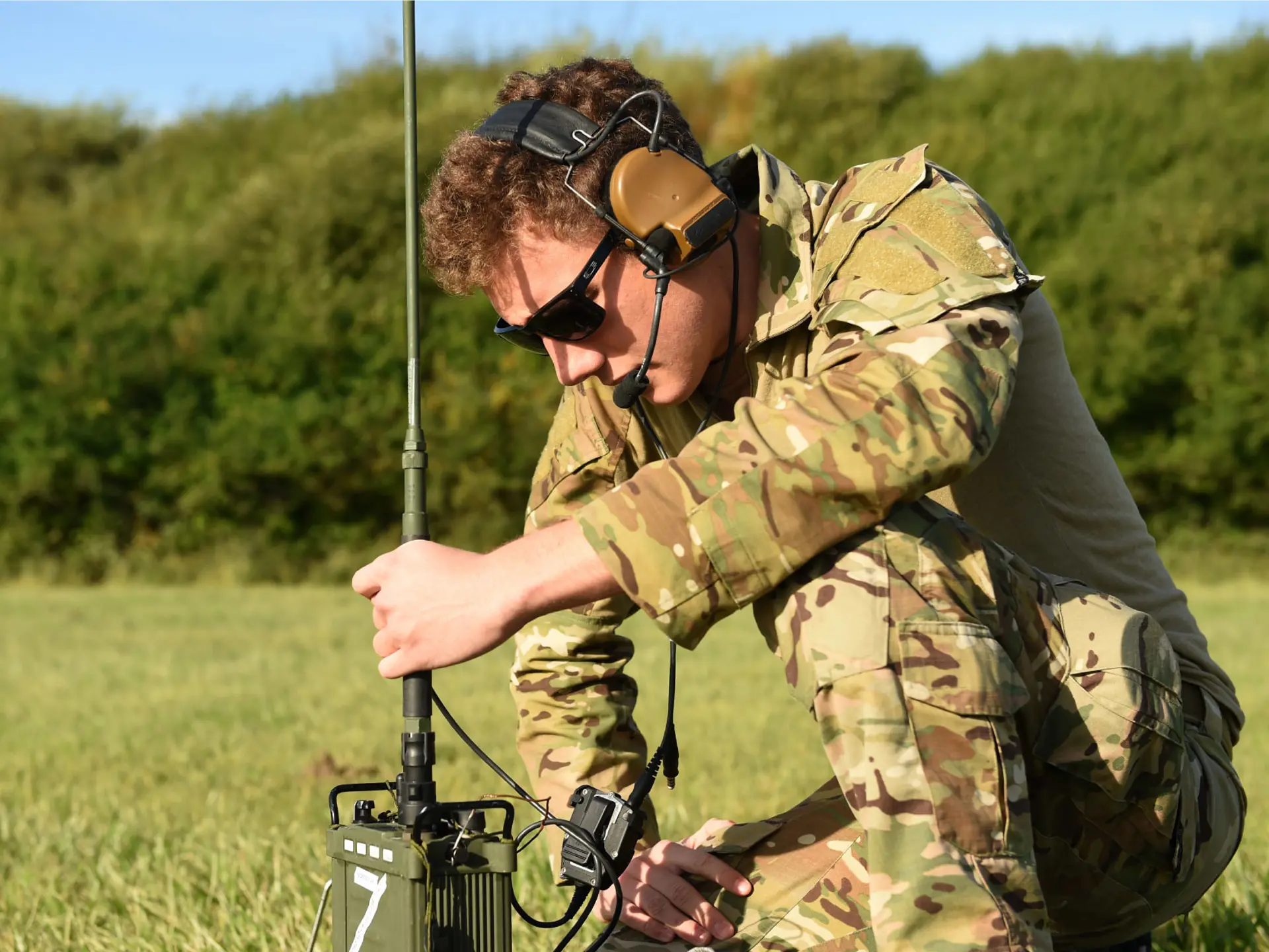 Solider sitting on grass and testing HF radio